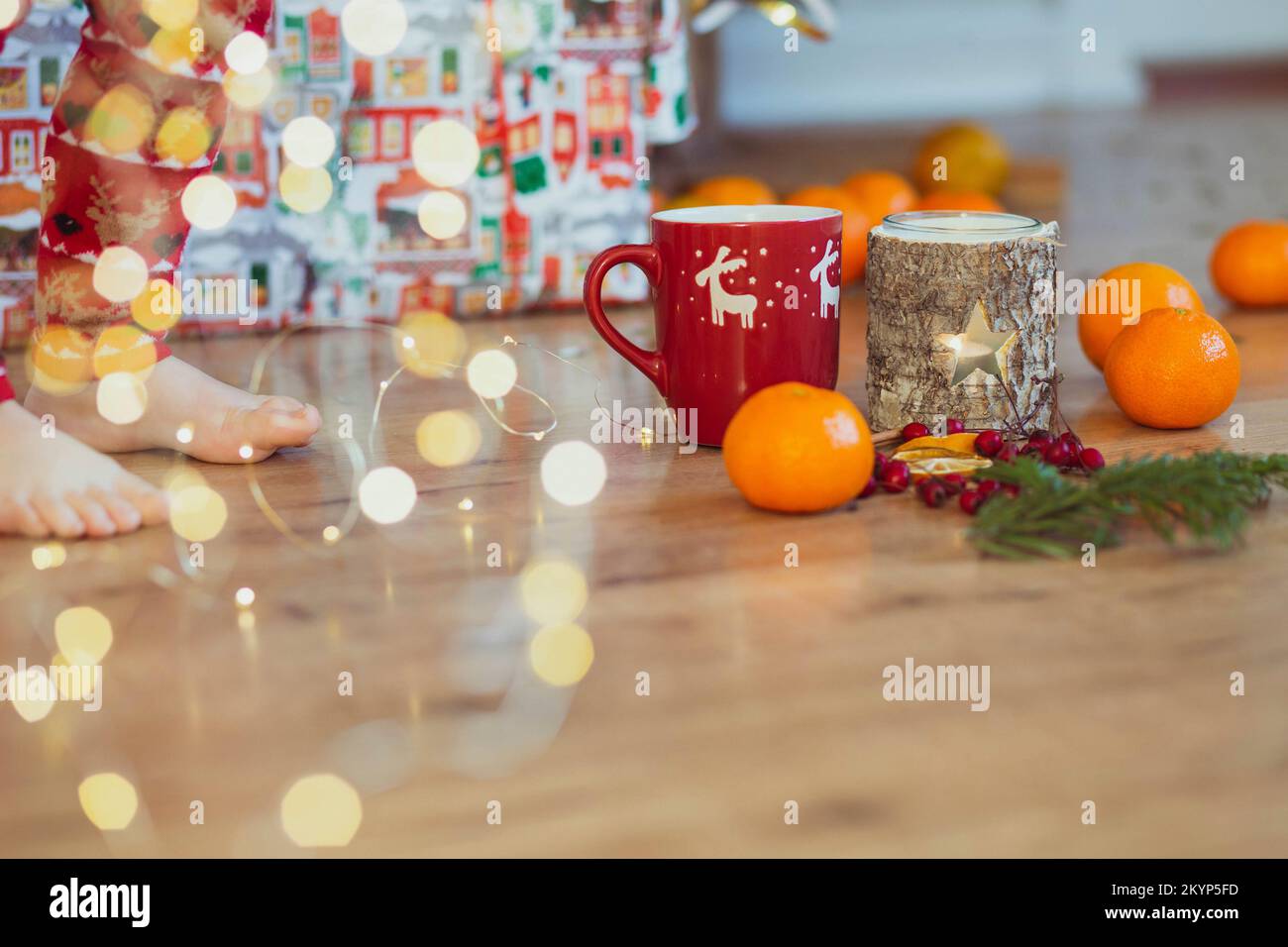 I piedi del bambino vicino alla decorazione di natale nel soggiorno Foto Stock