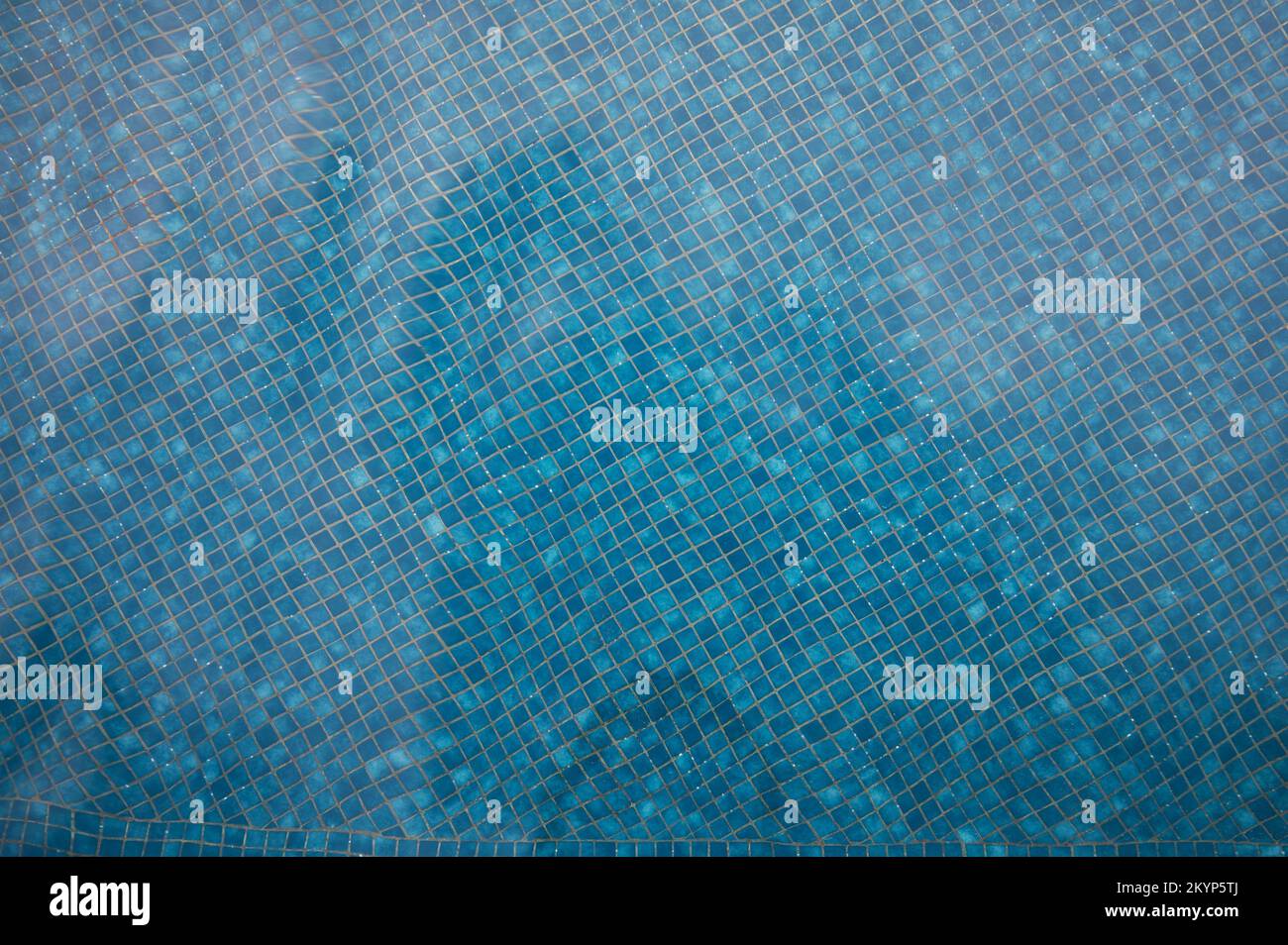 Piccole piastrelle di ceramica quadrate blu sotto lo sfondo dell'acqua della piscina Foto Stock