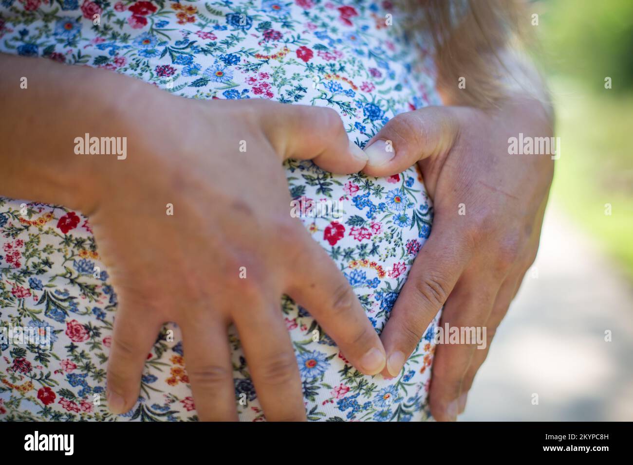 Donna incinta che forma un cuore con le dita Foto Stock