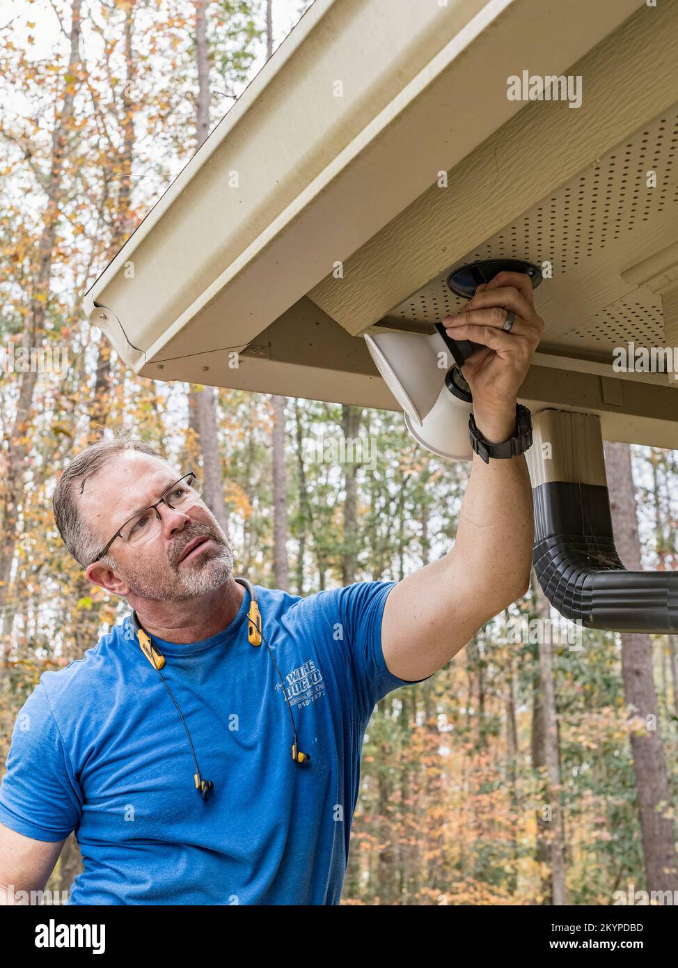Elettricista o handyman che regola le luci di sicurezza esterne o l'illuminazione su una casa residenziale. Foto Stock
