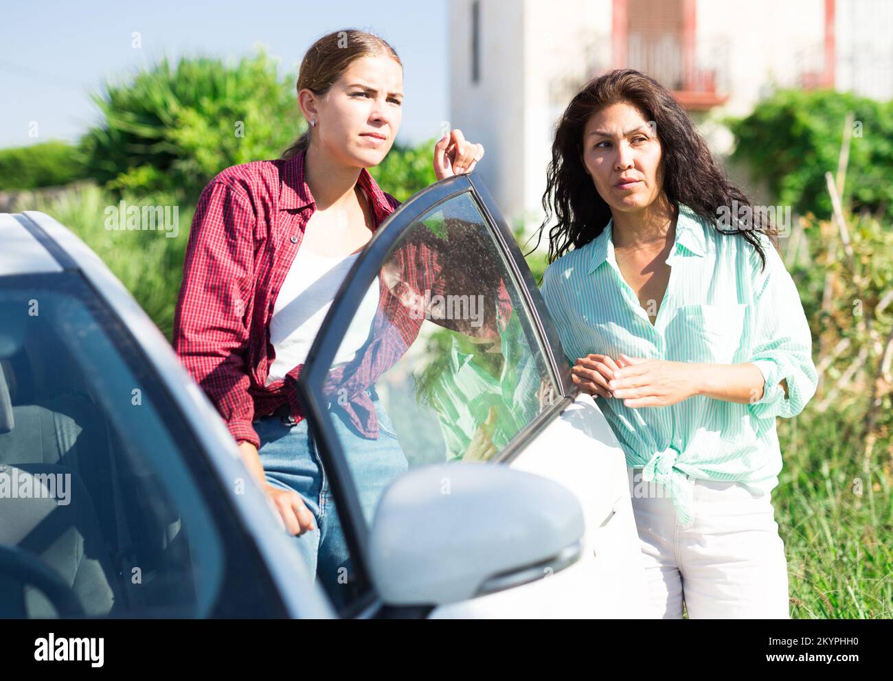 Due donne concentrate agricoltori discutere vicino auto in fattoria Foto Stock