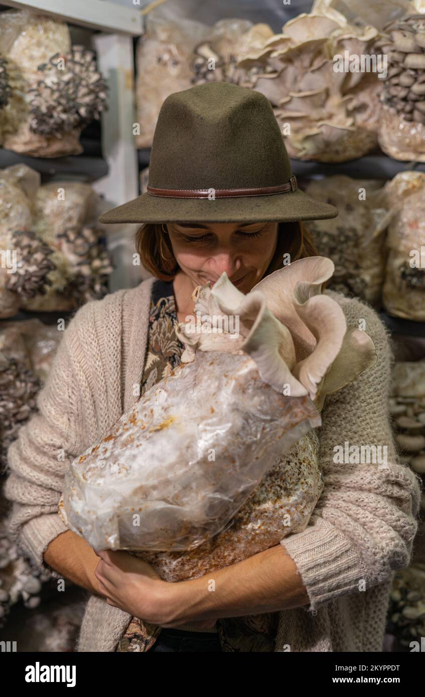 Giovane donna che tiene terreno coltivato con funghi di ostriche e sniffing esso Foto Stock
