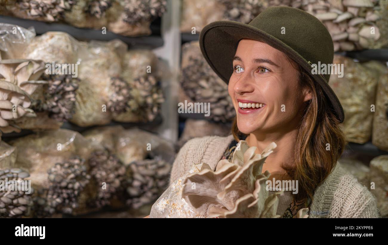 Giovane donna sorridente che tiene funghi di ostriche in fattoria funghi Foto Stock