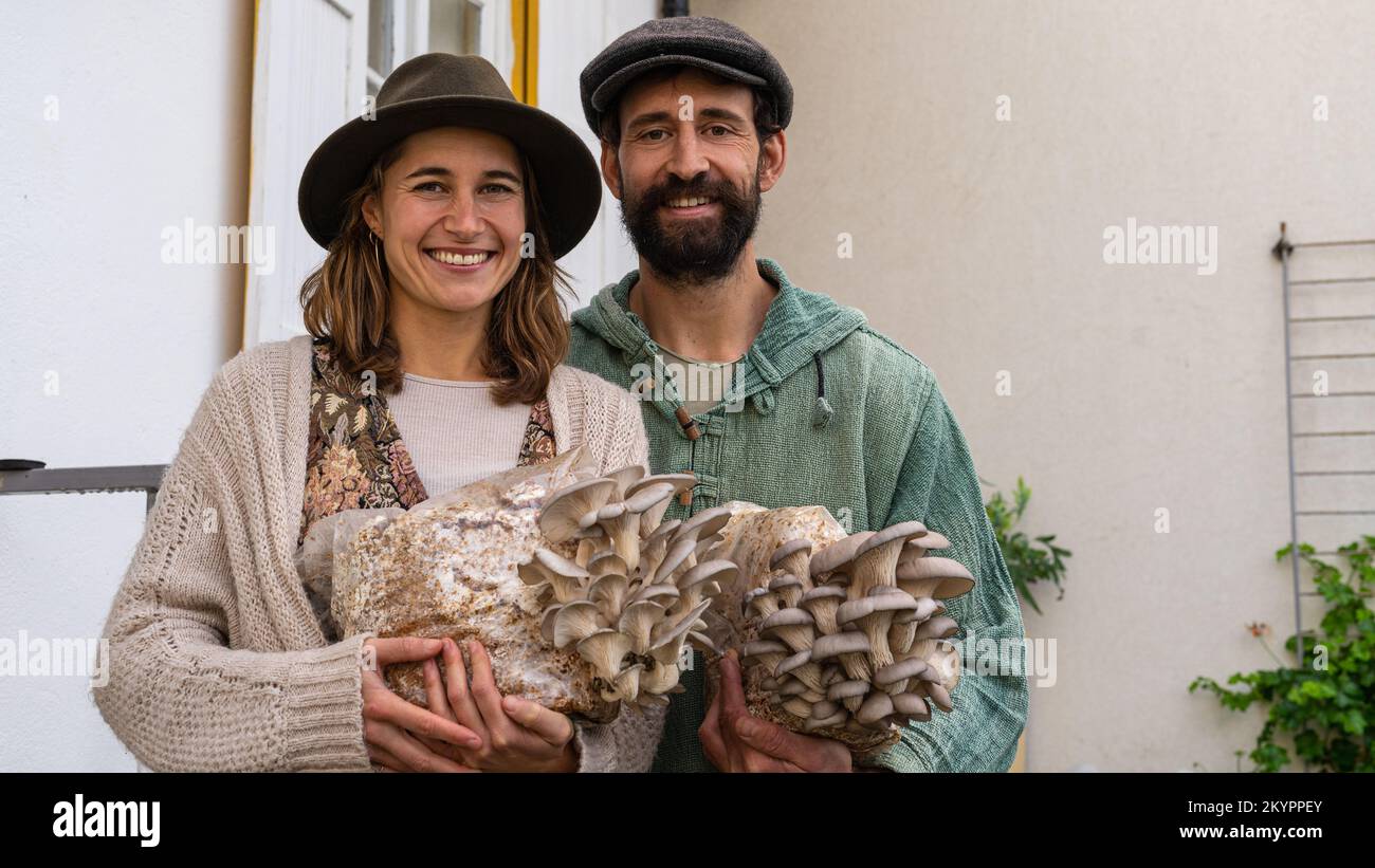 felice coppia contadina che tiene blocchi di funghi ostriche Foto Stock