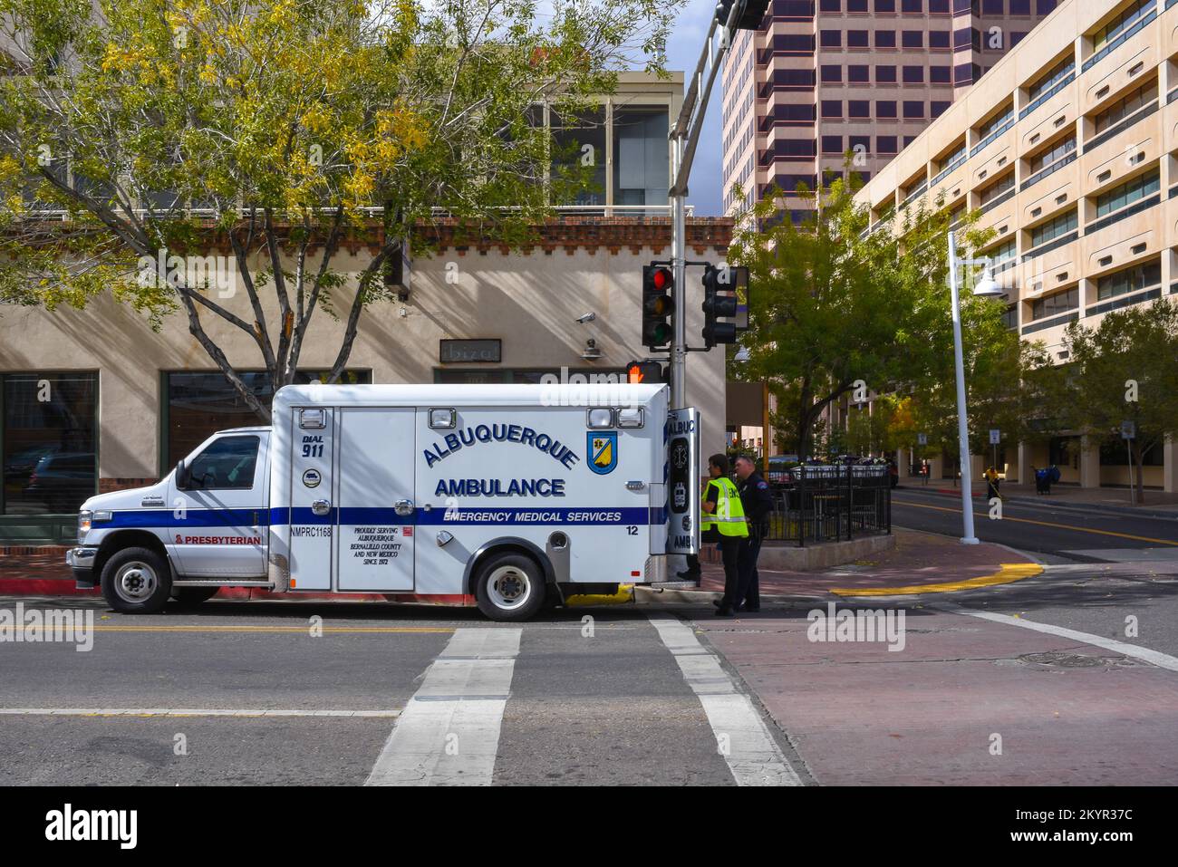 Un'ambulanza parcheggiata in strada nel centro di Albuquerque, New Mexico, con forze dell'ordine e paramedico in piedi sul retro, USA. Foto Stock