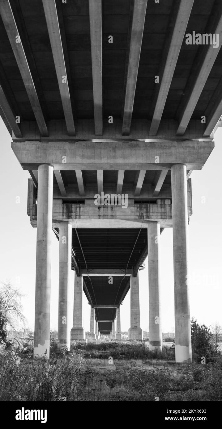 Sotto il ponte. Colonne di ponte in cemento. Costruzione prospettica da sotto il ponte. Nessuno, architettura astratta, foto in bianco e nero Foto Stock