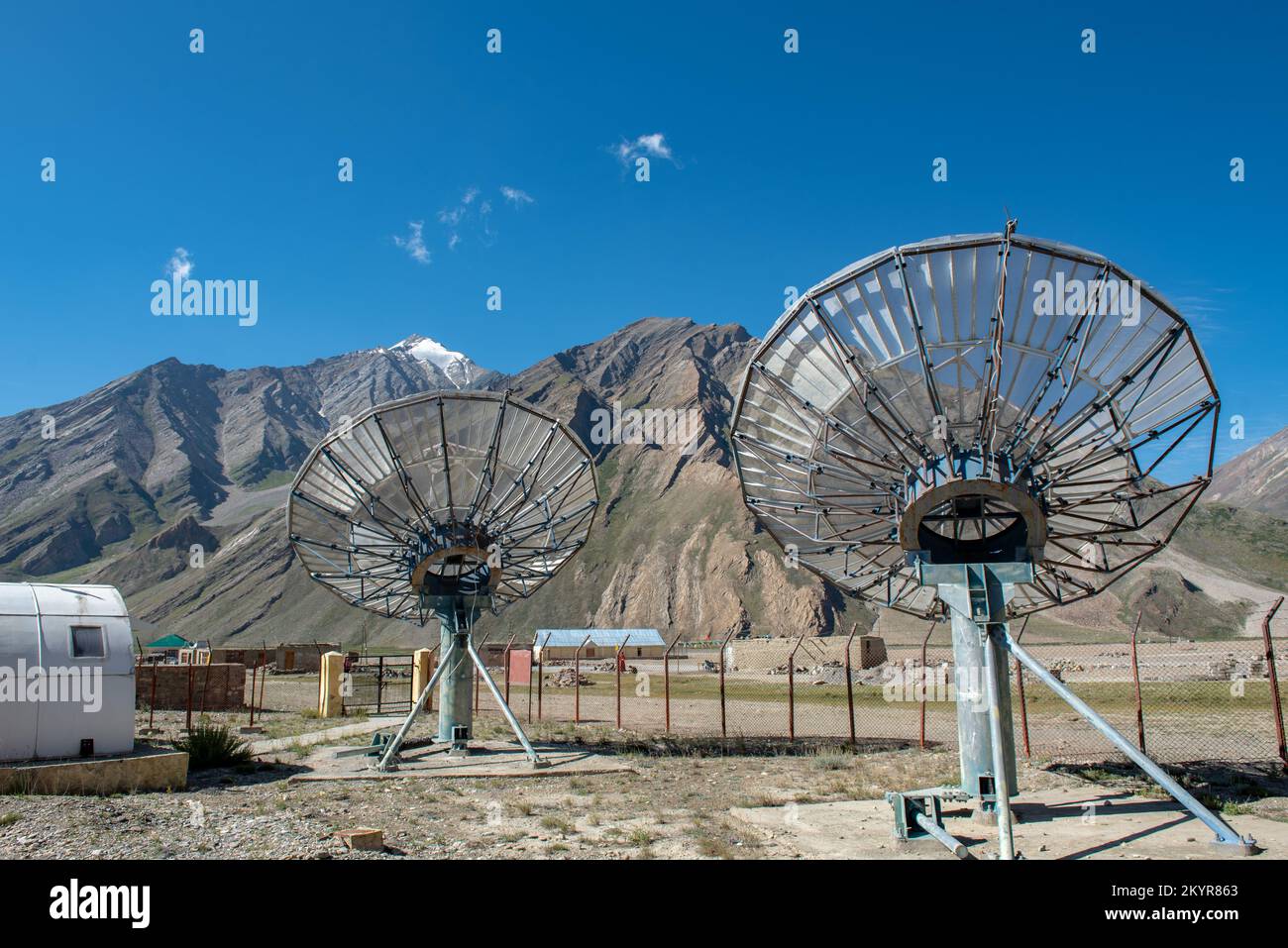Comunicazione satellitare piatti rete tecnologia in zona rurale con la gamma di montagna e cielo blu sfondo. Foto Stock