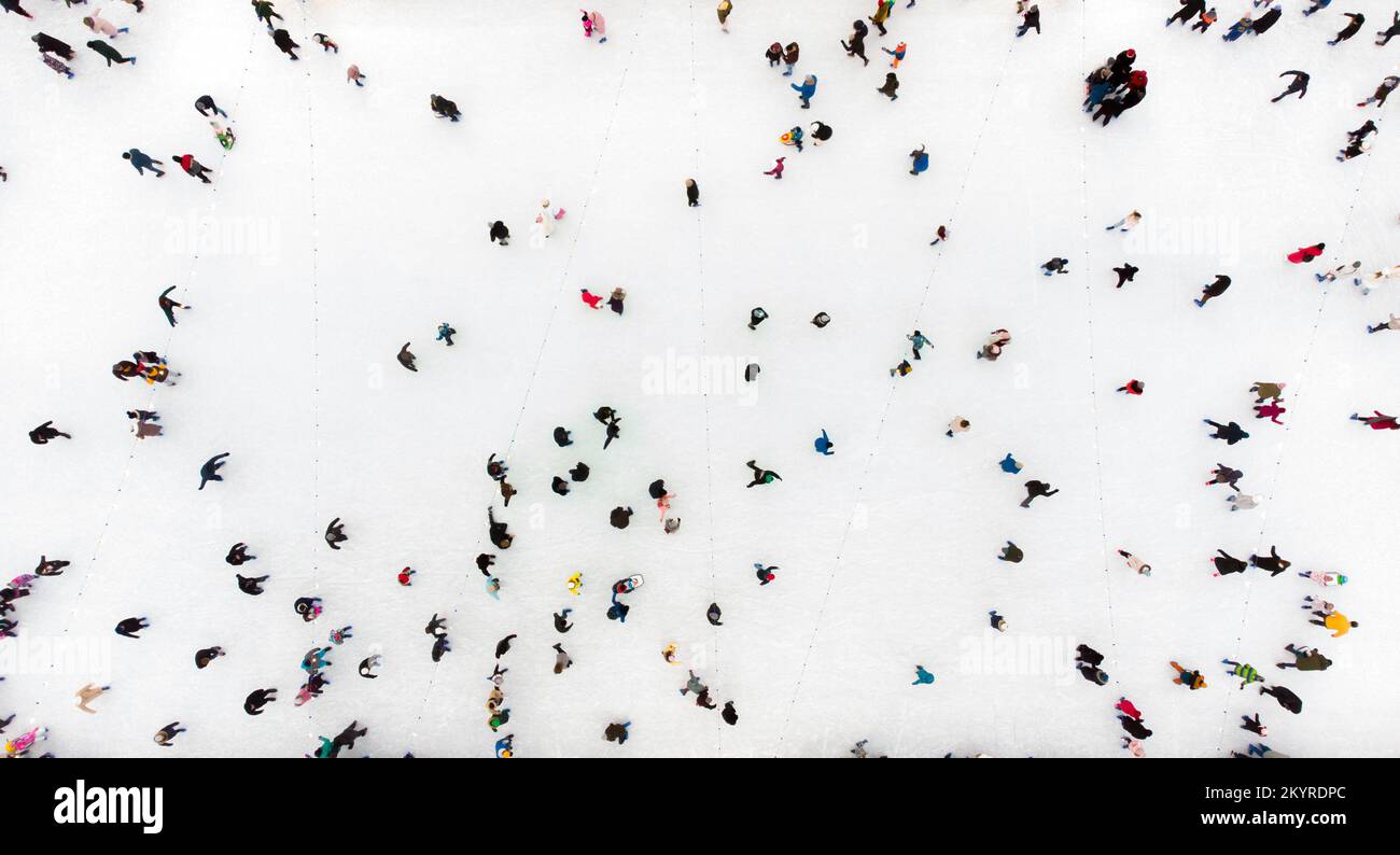 Persone che pattinare su una pista di pattinaggio su ghiaccio all'aperto. Vista dall'alto. Molta gente che pattinando sul ghiaccio della pista. Vista aerea del drone. Bella Skating Sport e attività invernali all'aperto sfondo Foto Stock