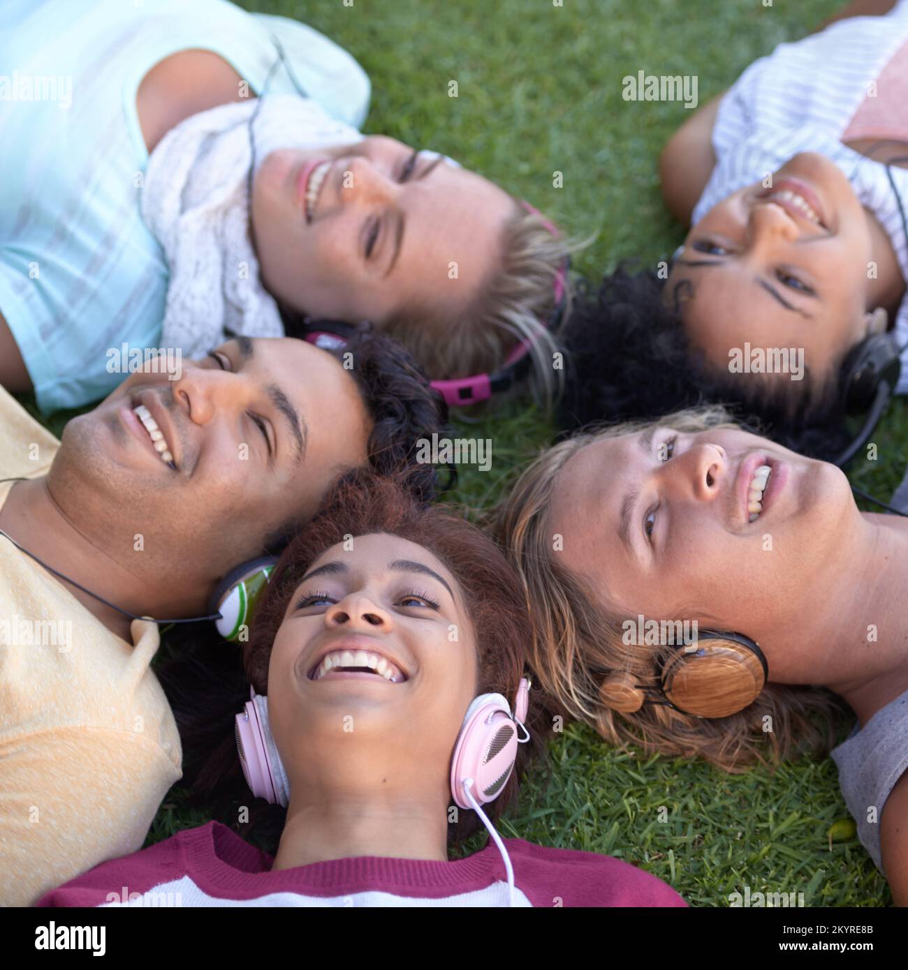 Condividere il nostro amore per la musica. Un gruppo di giovani studenti sdraiati sull'erba e che ascoltano musica. Foto Stock