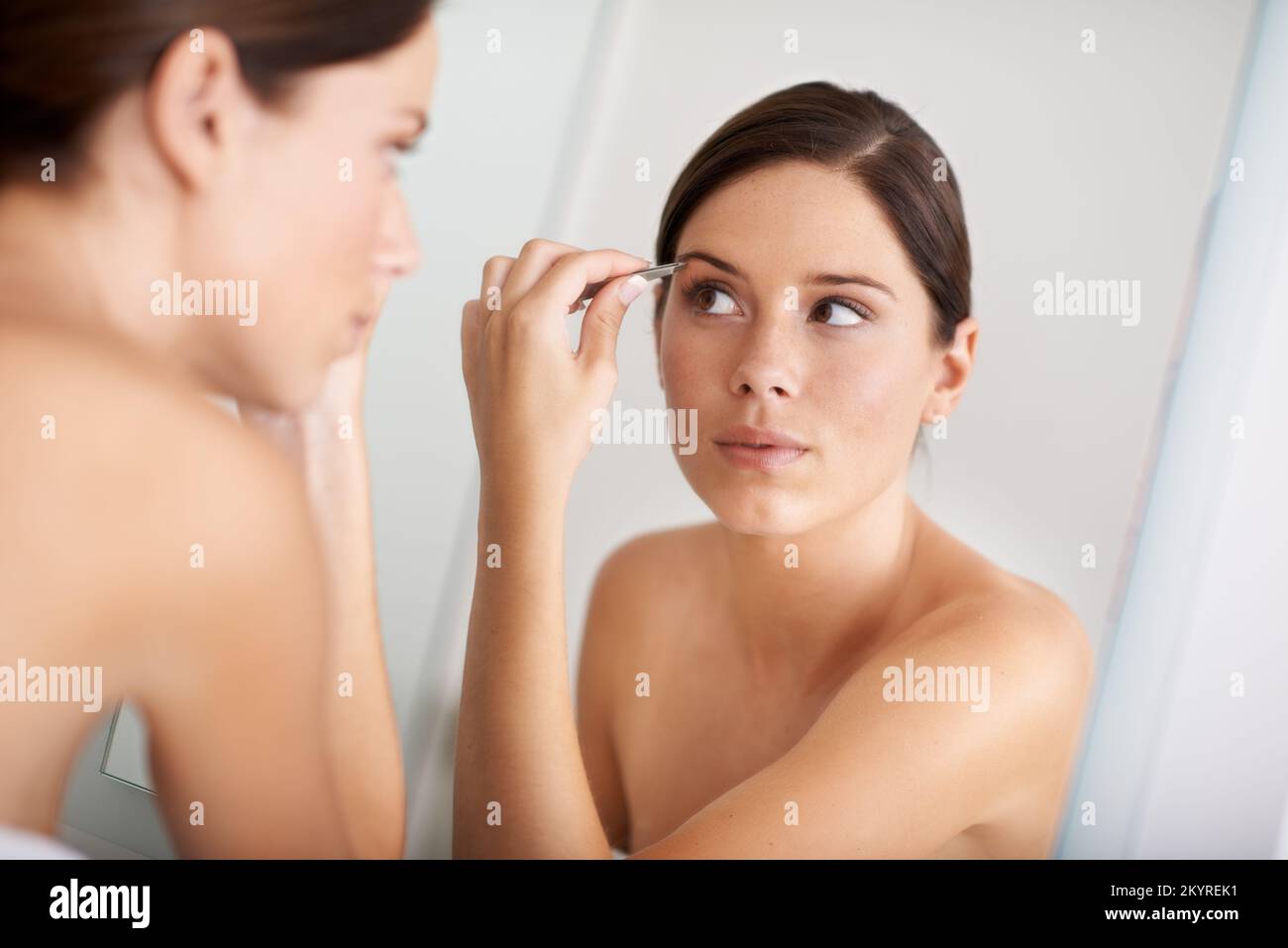 Mantenere le sue sopracciglia guardare bene. Una bella giovane donna che le ciglia nello specchio. Foto Stock