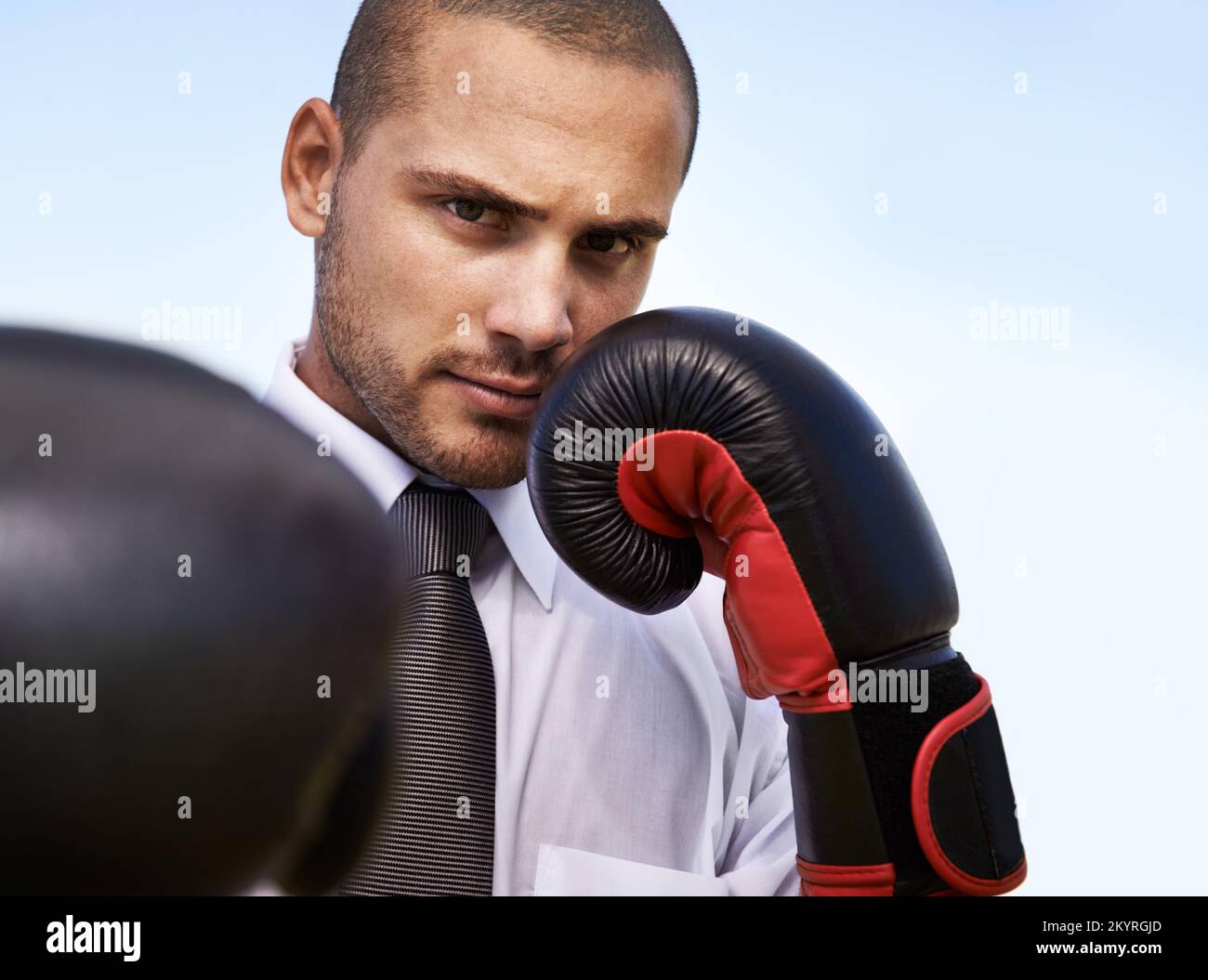 Lotta per l'eccellenza aziendale. Un giovane uomo d'affari che indossa guanti da boxe. Foto Stock