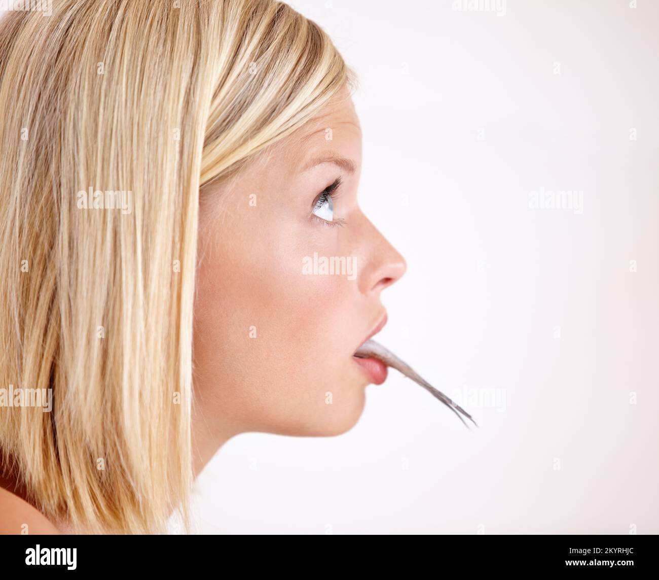 Gli alimenti di mare non realmente per lei. Profilo di una bella giovane donna che mangia un pesce intero. Foto Stock