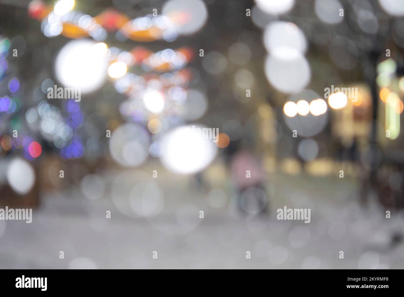 Sfondo sfocato astratto. Persone che camminano per strada di alberi di Natale decorati con illuminazione luminosa, luci incandescenti e ghirlande in città durante le pesanti nevicate nella notte d'inverno Foto Stock