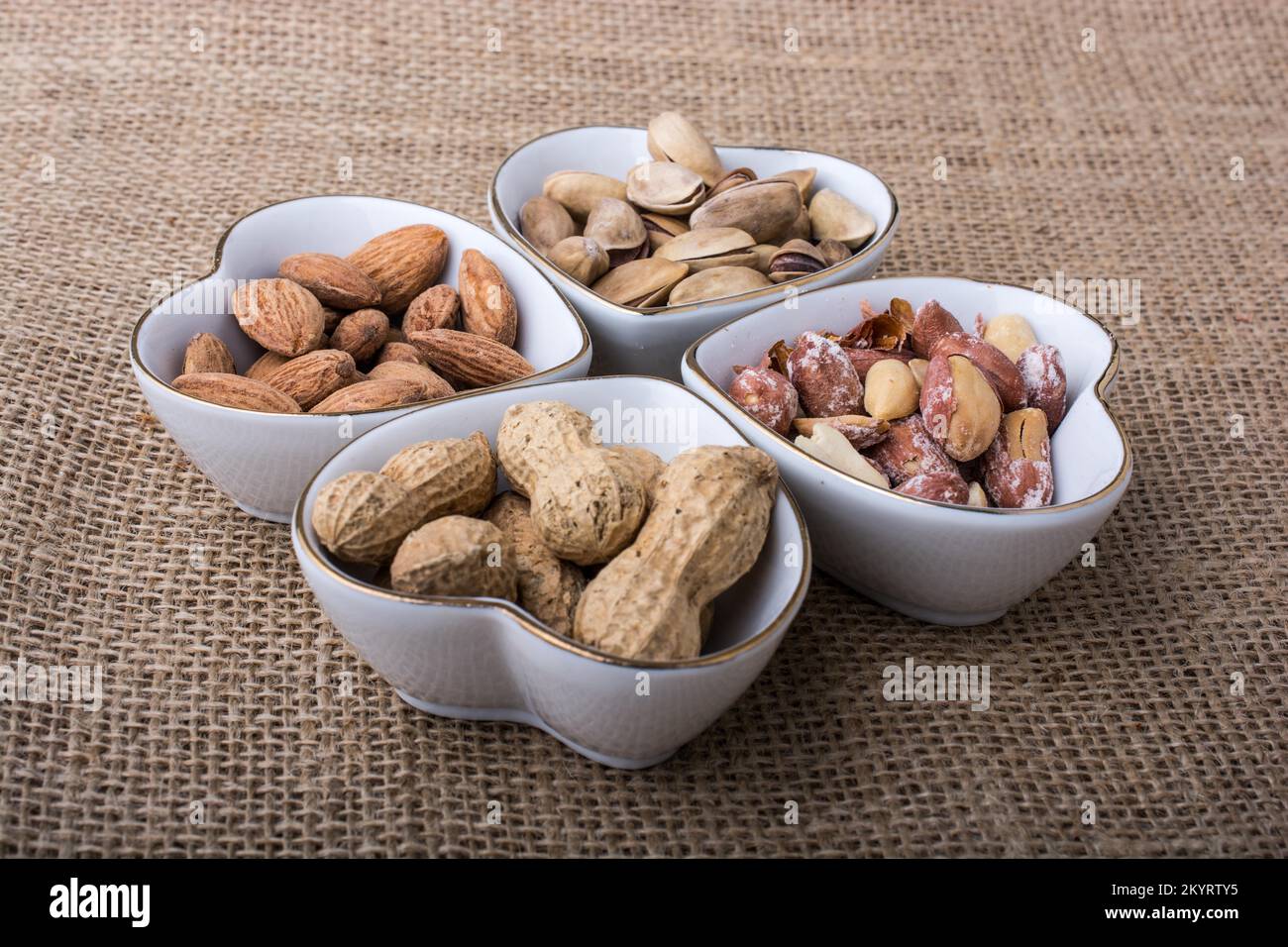 Arachidi e mandorle in piatti a forma di cuore su tela Foto Stock