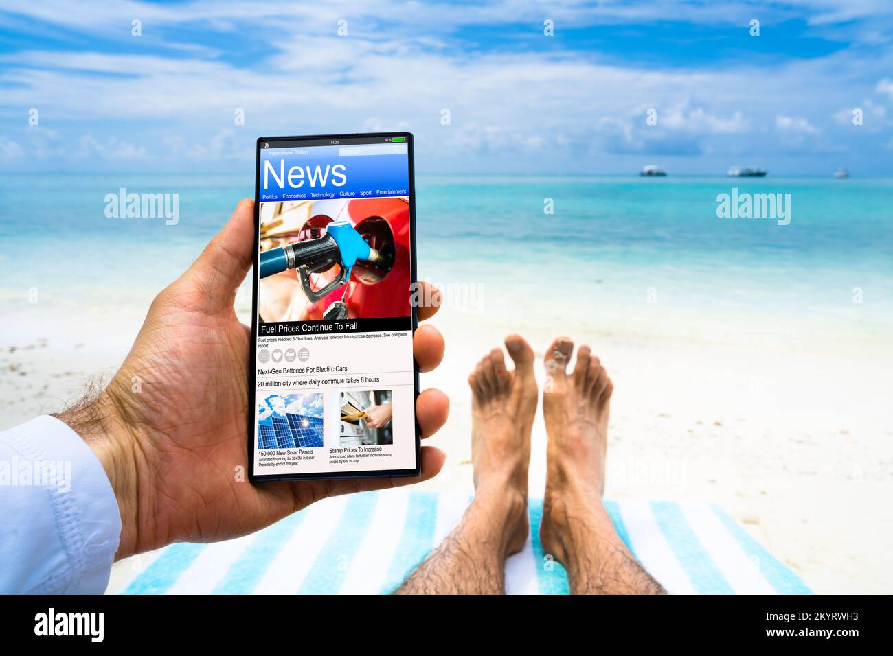 Uomo che legge le notizie sul telefono digitale alla spiaggia Foto Stock
