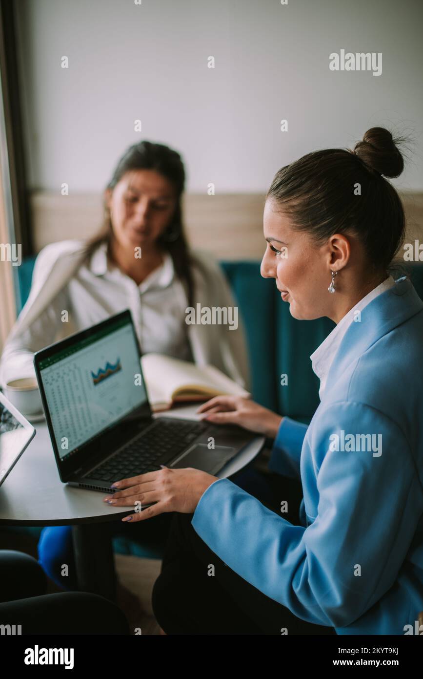 Bussiness donna che lavora sul notebook e che parla con i suoi amici del loro ultimo progetto Foto Stock