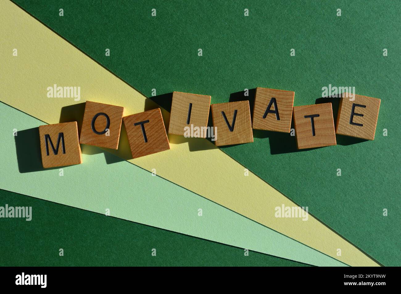 Motivare, parola in lettere di legno alfabeto isolato su sfondo verde Foto Stock
