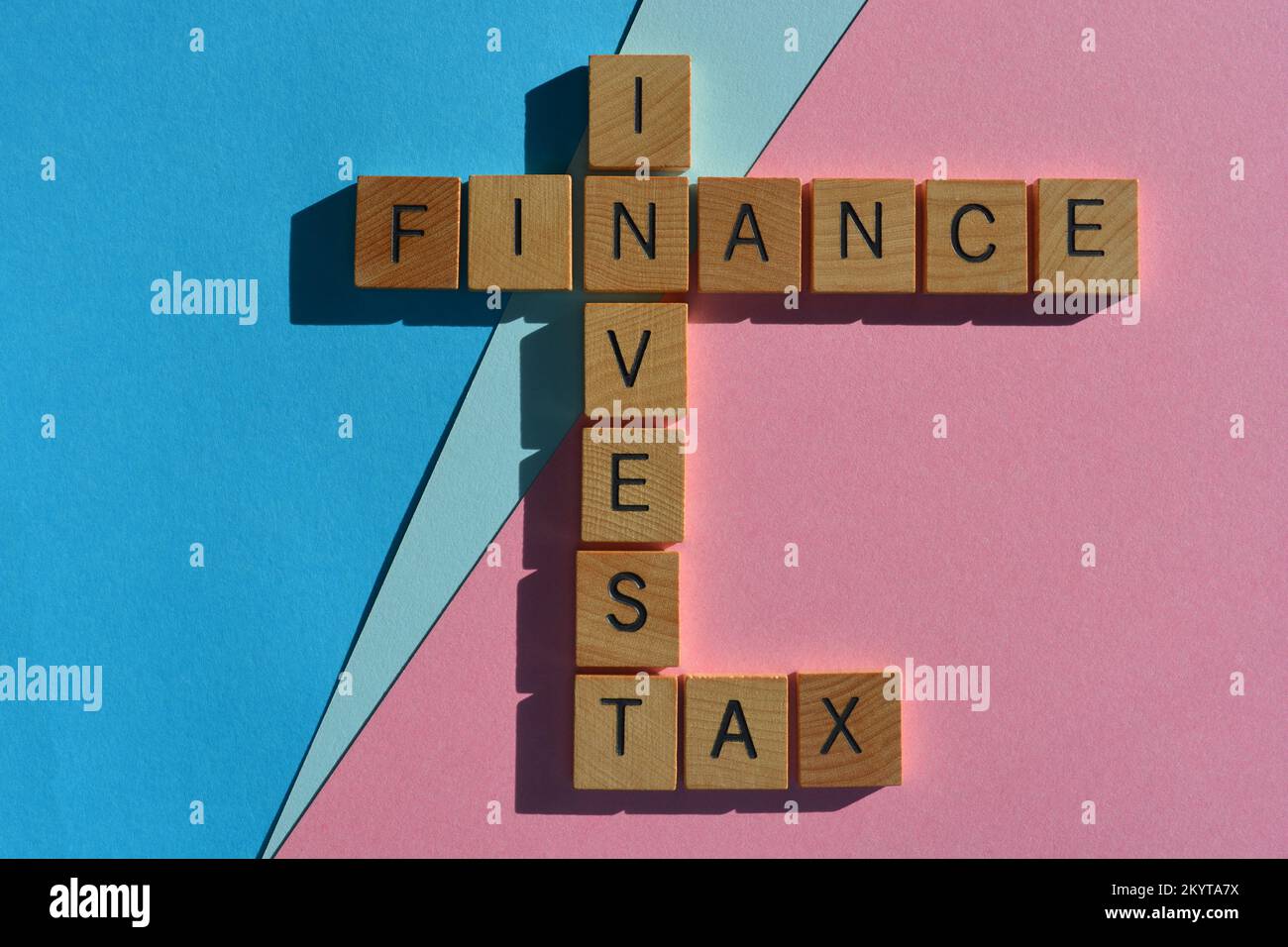 Finanza, investire, tasse, parole in legno alfabeto bollitori in forma di croce isolato su sfondo rosa e blu Foto Stock