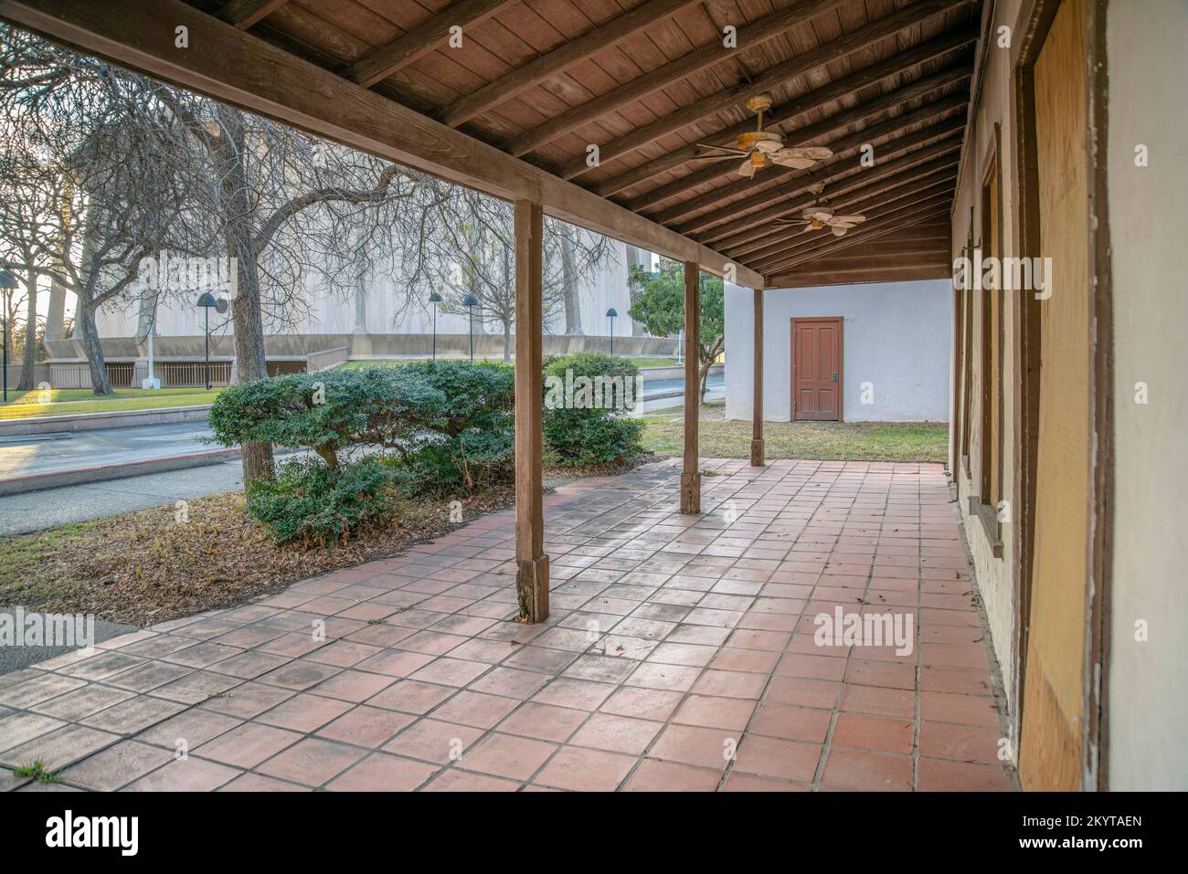 Portico anteriore di un vecchio edificio storico e abbandonato a San Antonio Texas. Esterno di una struttura intatta che ha una porta in legno, finestre coperte Foto Stock