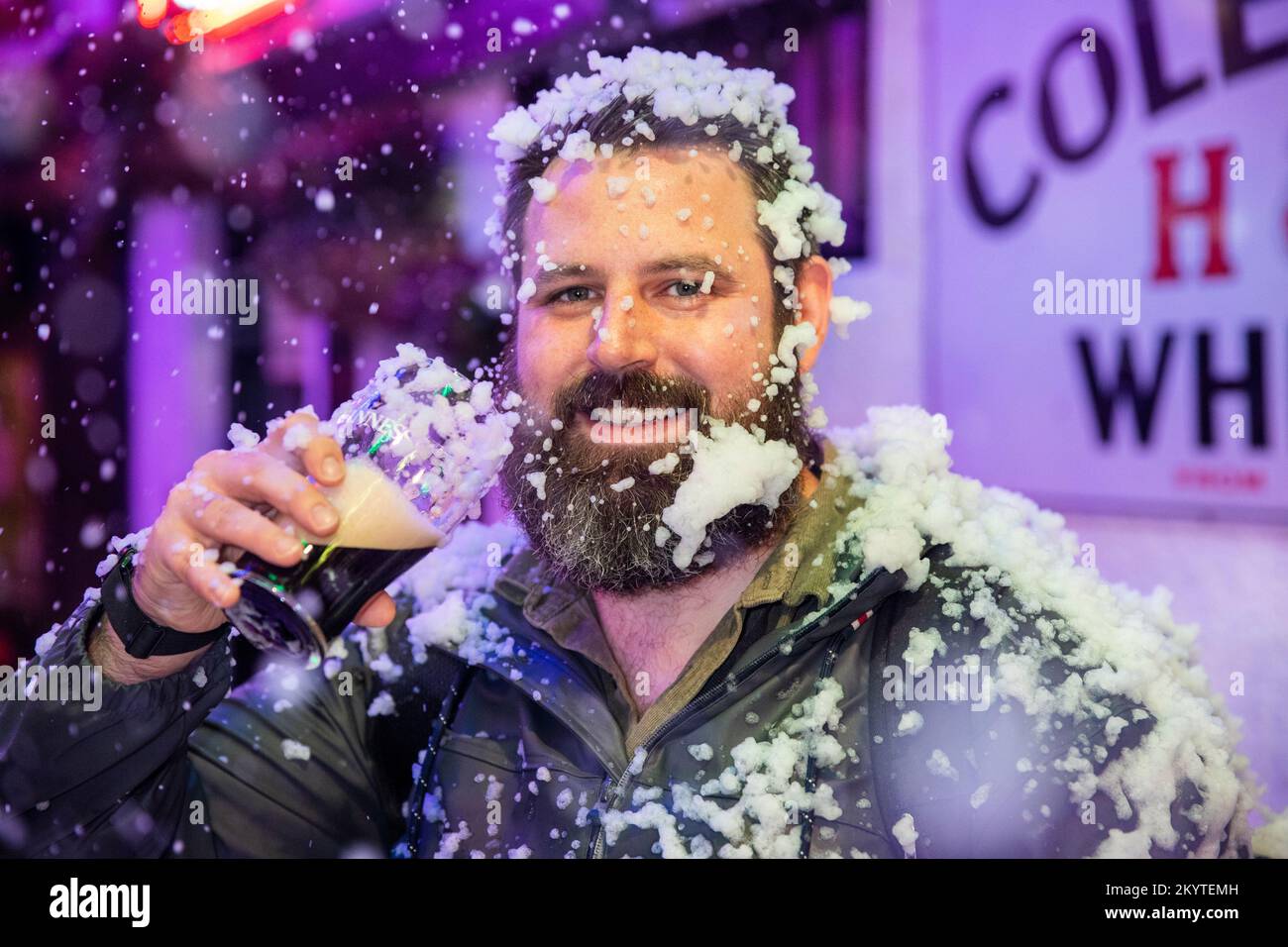 Chris Laughlin sulle strade acciottolate di Commercial Court fuori del bar Duke of York a Belfast, mentre Guinness ha dato vita al suo iconico annuncio natalizio con una macchina da neve, mentre gli ospiti sono stati accolti in una pinta per iniziare la stagione festiva. Foto Stock