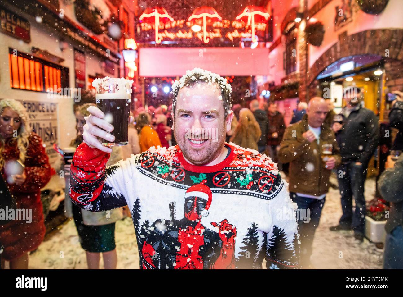 David Gibson sulle strade acciottolate di Commercial Court fuori del bar Duke of York a Belfast, mentre Guinness ha dato vita al suo iconico annuncio natalizio con una macchina da neve, mentre gli ospiti sono stati accolti da una pinta per iniziare la stagione festiva. Foto Stock