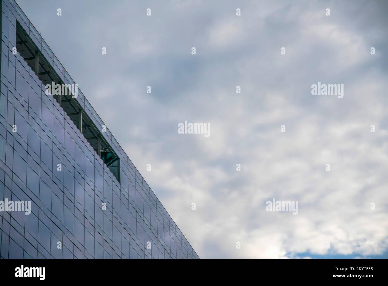 Vista ad angolo basso di un edificio di vetro con alta terrazza elevata - Austin, Texas. Edificio in vetro con un riflesso del cielo nuvoloso sopra. Foto Stock