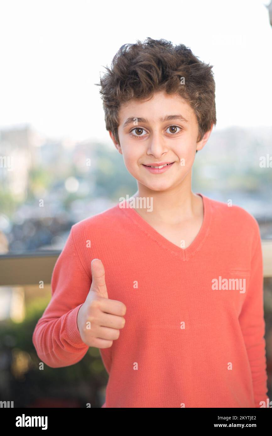 11 anni ragazzo che mostra i pollici in su gesto Foto Stock