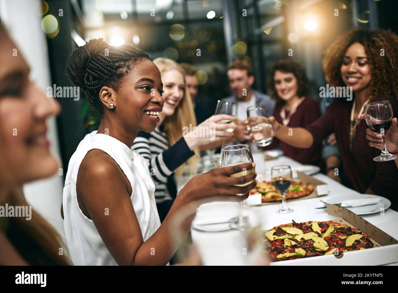 Diversità, cena e gruppo di persone brinda festa insieme a festa. Amici, felici e festeggiano con cibo, vino e amicizia per l'amore Foto Stock