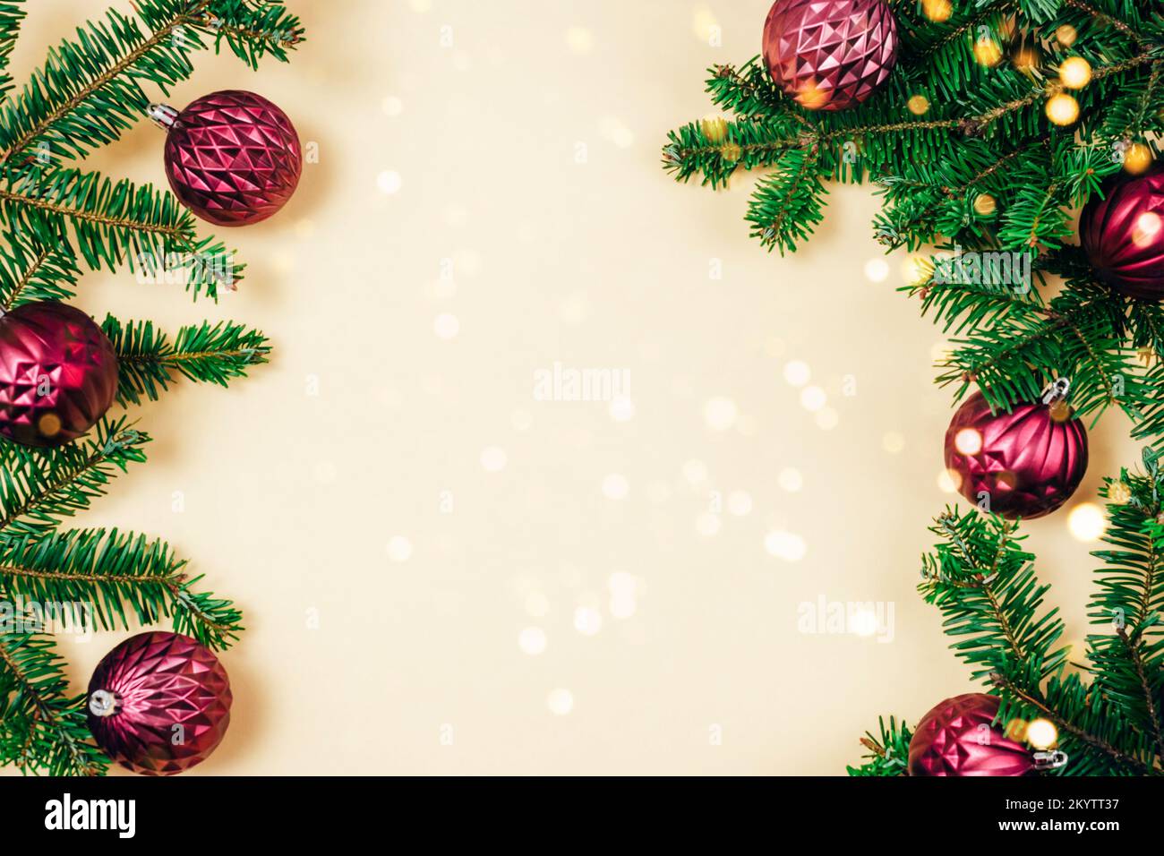 Rami di abete e baubles di Natale viola con luci bokeh dorate su sfondo beige. Vista dall'alto, disposizione piatta, spazio di copia Foto Stock