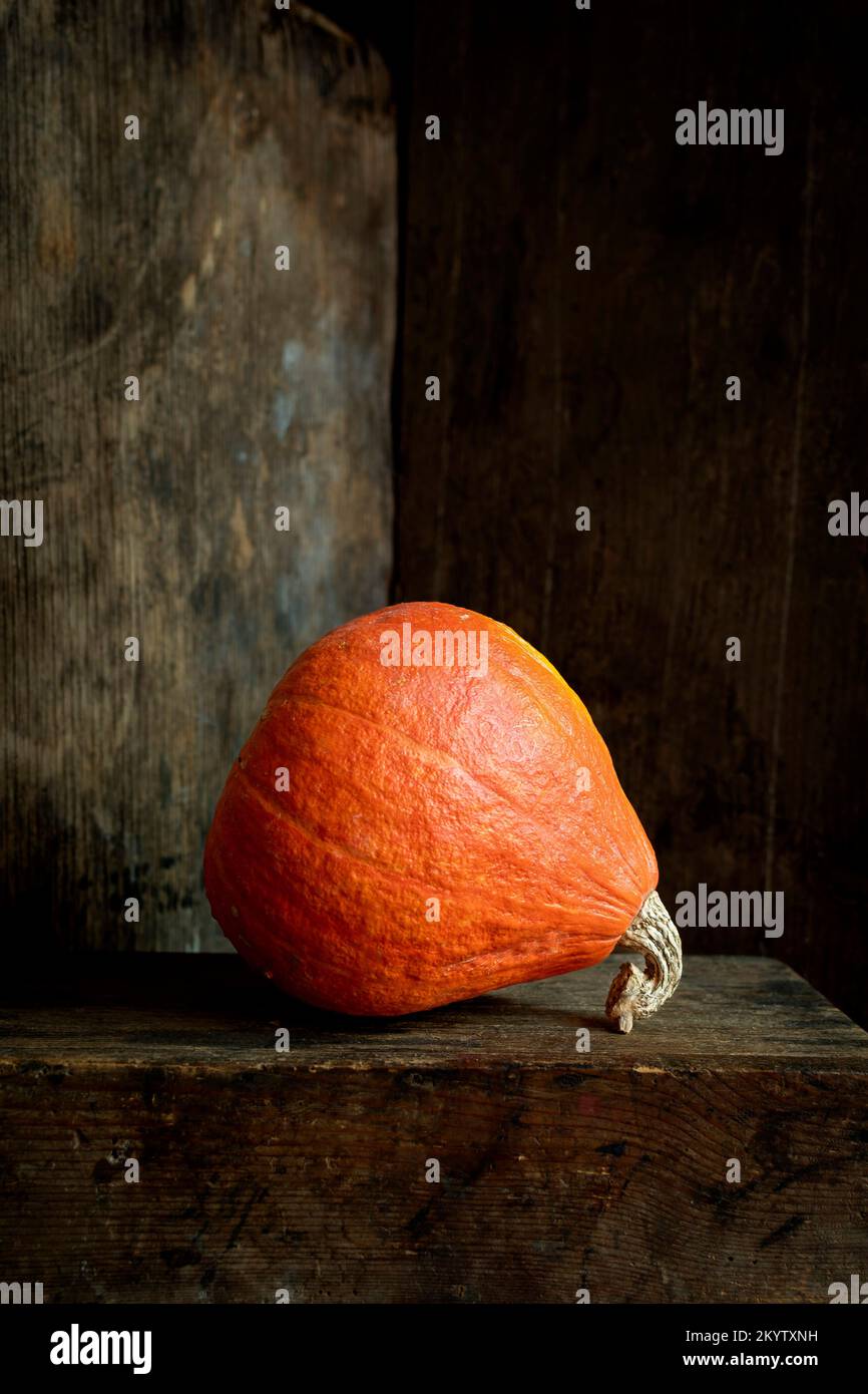 Zucca arancione matura appoggiata su un tavolo di legno in un ambiente rustico Foto Stock
