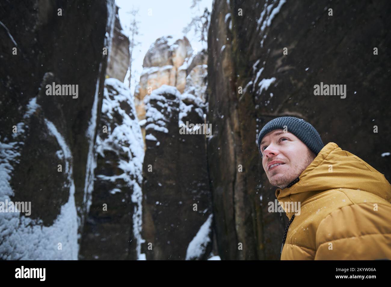 Portrat dell'uomo in mezzo a rocce innevate durante la giornata gelosa d'inverno. Foto Stock