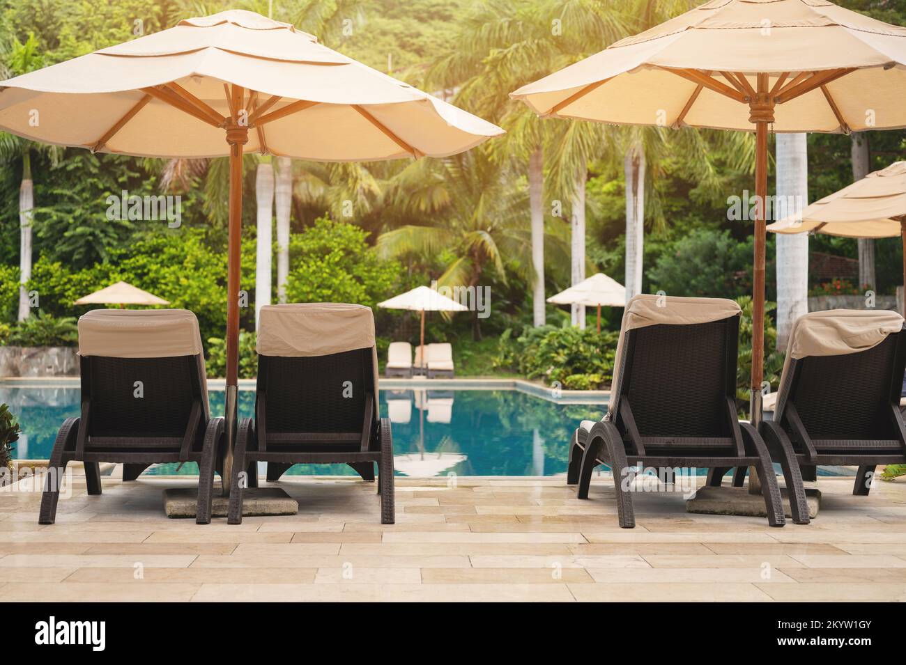 Sedie a sdraio e ombrellone accanto alla piscina nel resort dell'hotel nelle giornate di sole Foto Stock