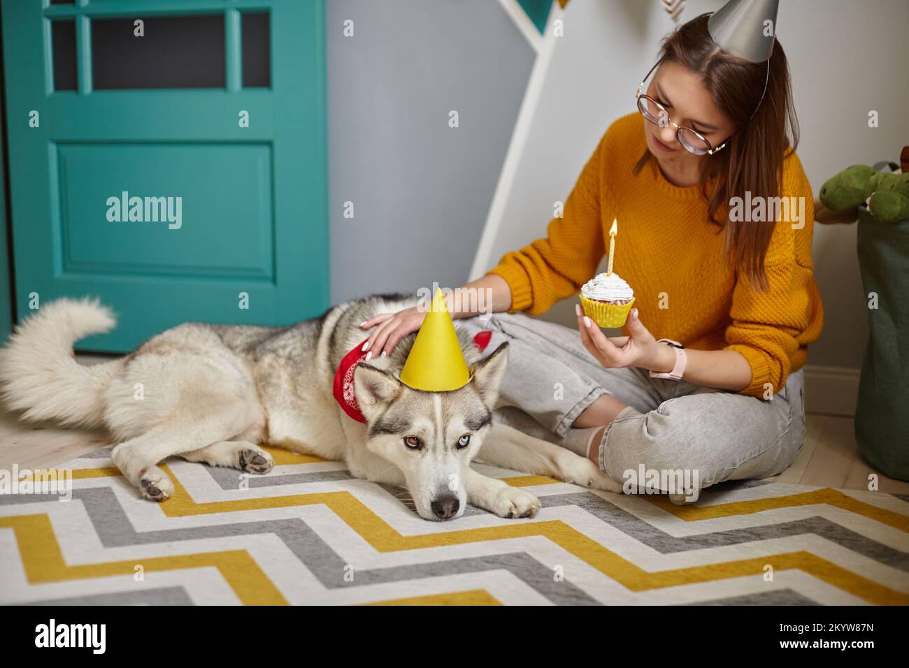 Festa di compleanno cane animale domestico, donna che si congratula con triste anziano animale domestico con compleanno cupcake buon compleanno Foto Stock