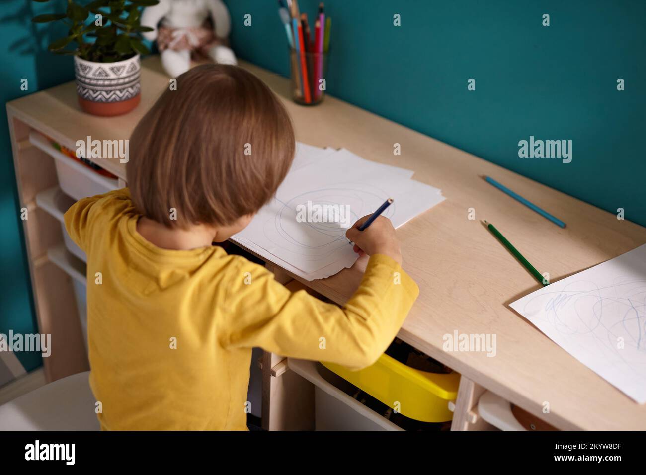 Disegno per bambini con matite colorate sedute al tavolo nella stanza dei bambini Foto Stock