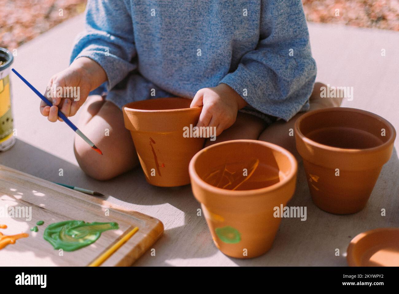 Bambina dipingere vasi di fiori fuori al sole a Saint Geo Foto stock - Alamy