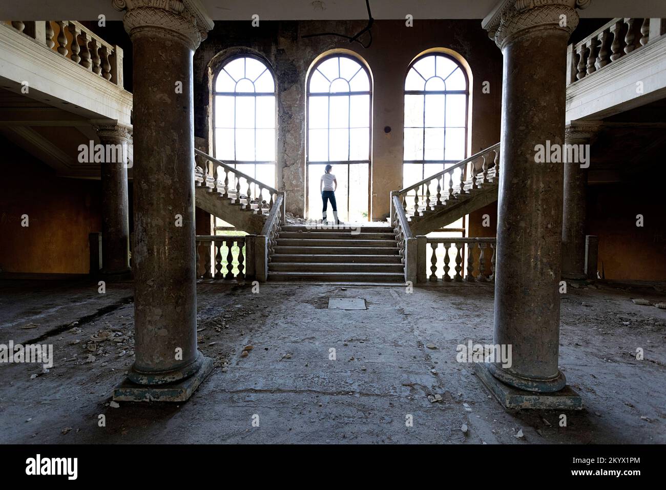 Donna turistica che esplora lo spettacolare complesso ex sovietico abbandonato del Sanatorium Metallurgist nella città termale di Tskaltubo vicino a Kutaisi, Georgia Foto Stock