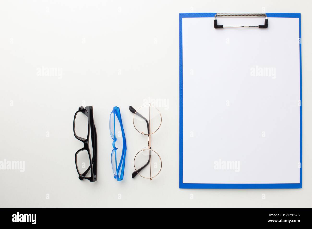 Molti occhiali diversi per la visione si trovano sul desktop vicino alla cartella per il testo. Foto Stock