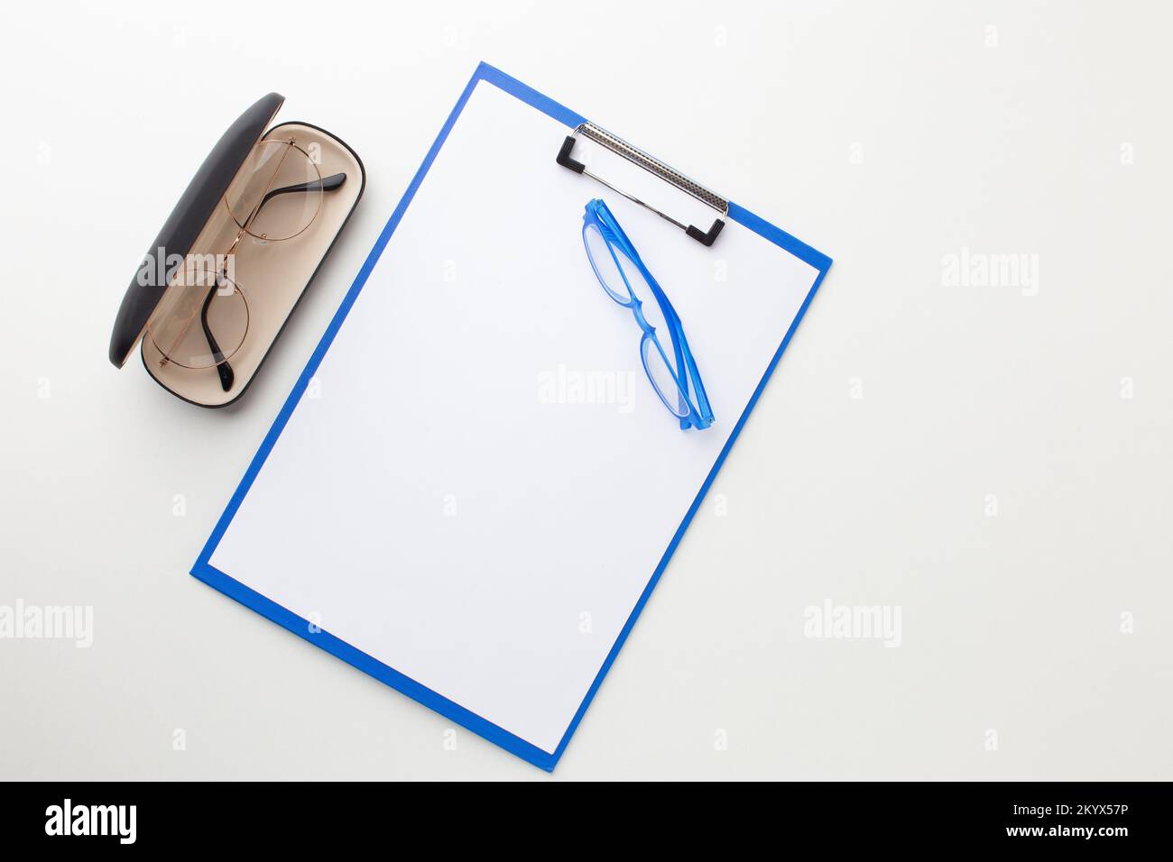 Occhiali in un caso accanto a una cartella blu per il testo sul desktop. Foto Stock