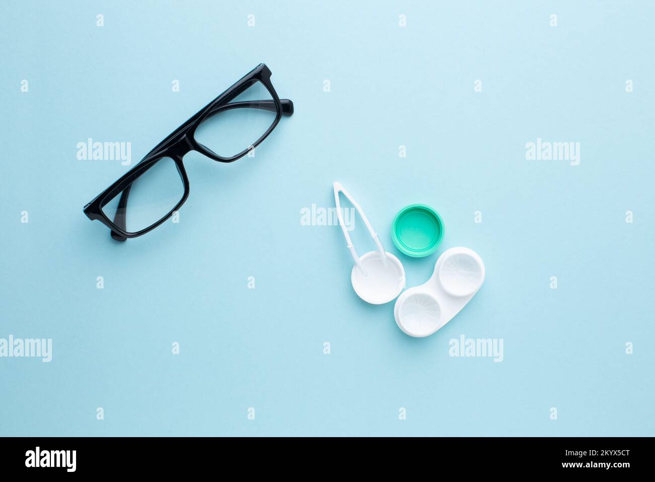 Occhiali e accessori per lenti a contatto: Un contenitore per lenti e pinzette su sfondo blu. Foto Stock