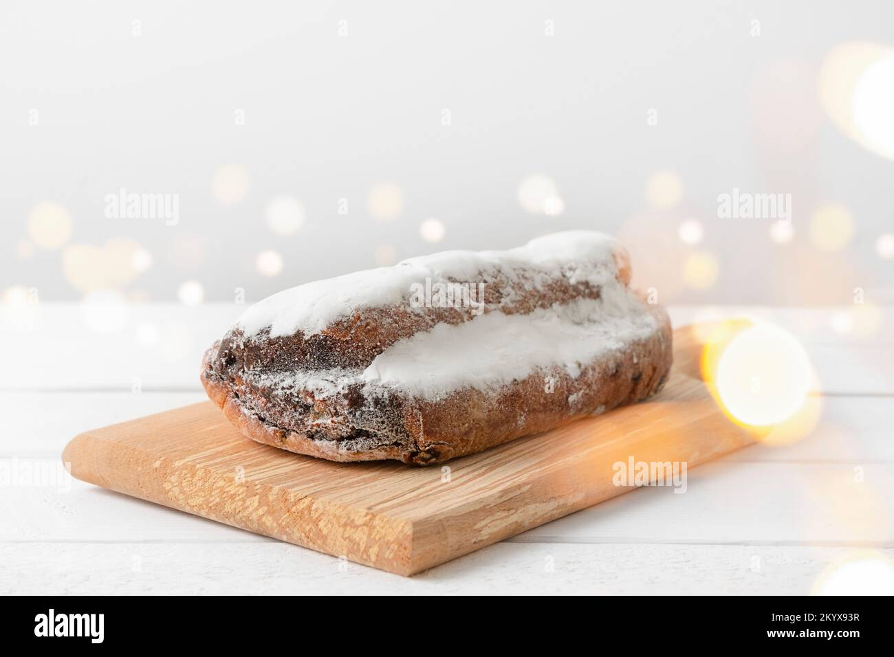 Torta di Natale stollen su sfondo di legno bianco con luci bokeh Foto Stock