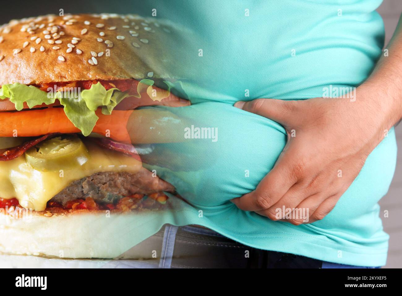 Obesità e cibo spazzatura. Uomo che tiene il suo pancia grasso e hamburger pieno. Foto Stock