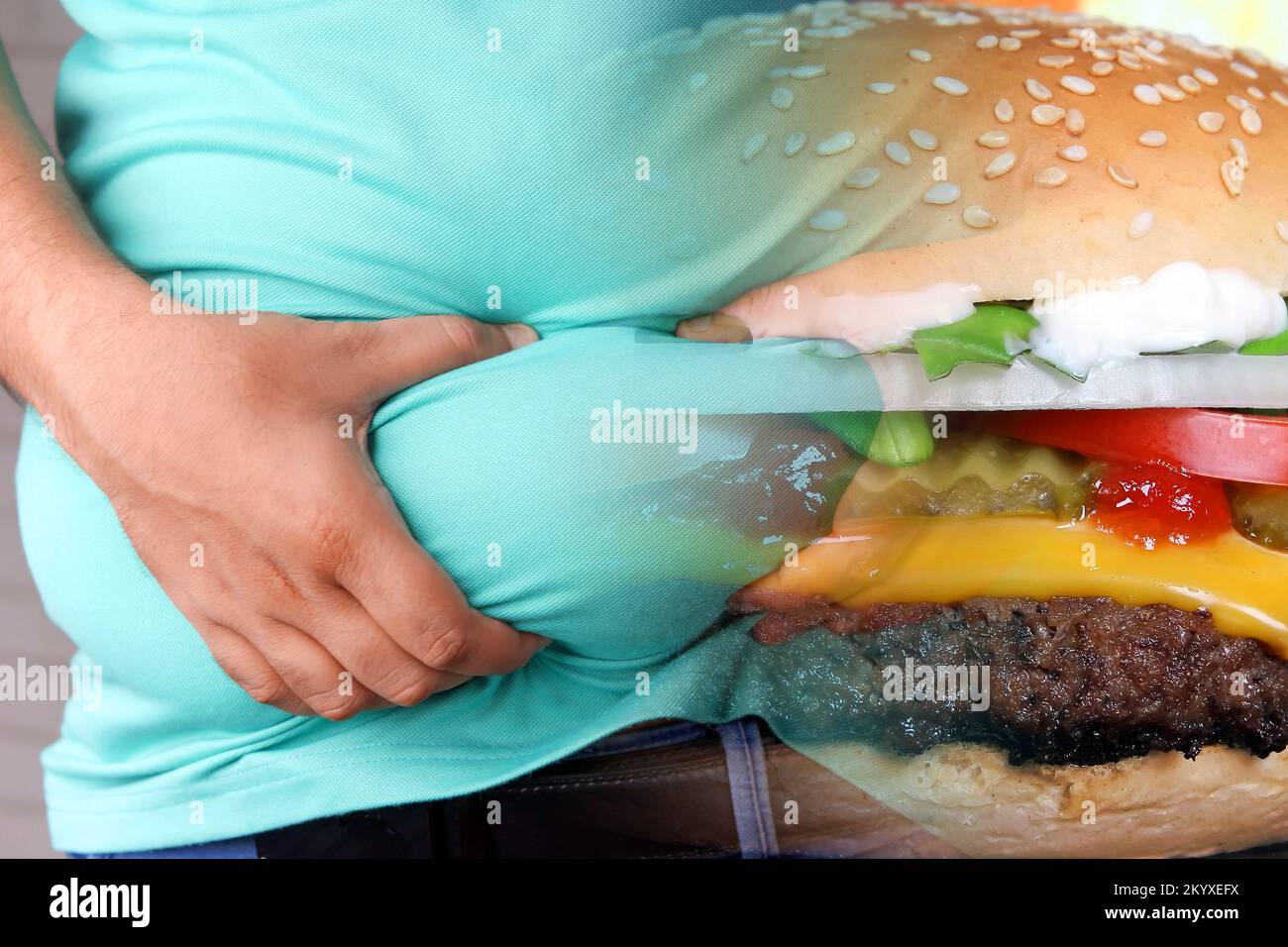 Obesità e cibo spazzatura. Uomo che tiene il suo pancia grasso e hamburger pieno. Foto Stock
