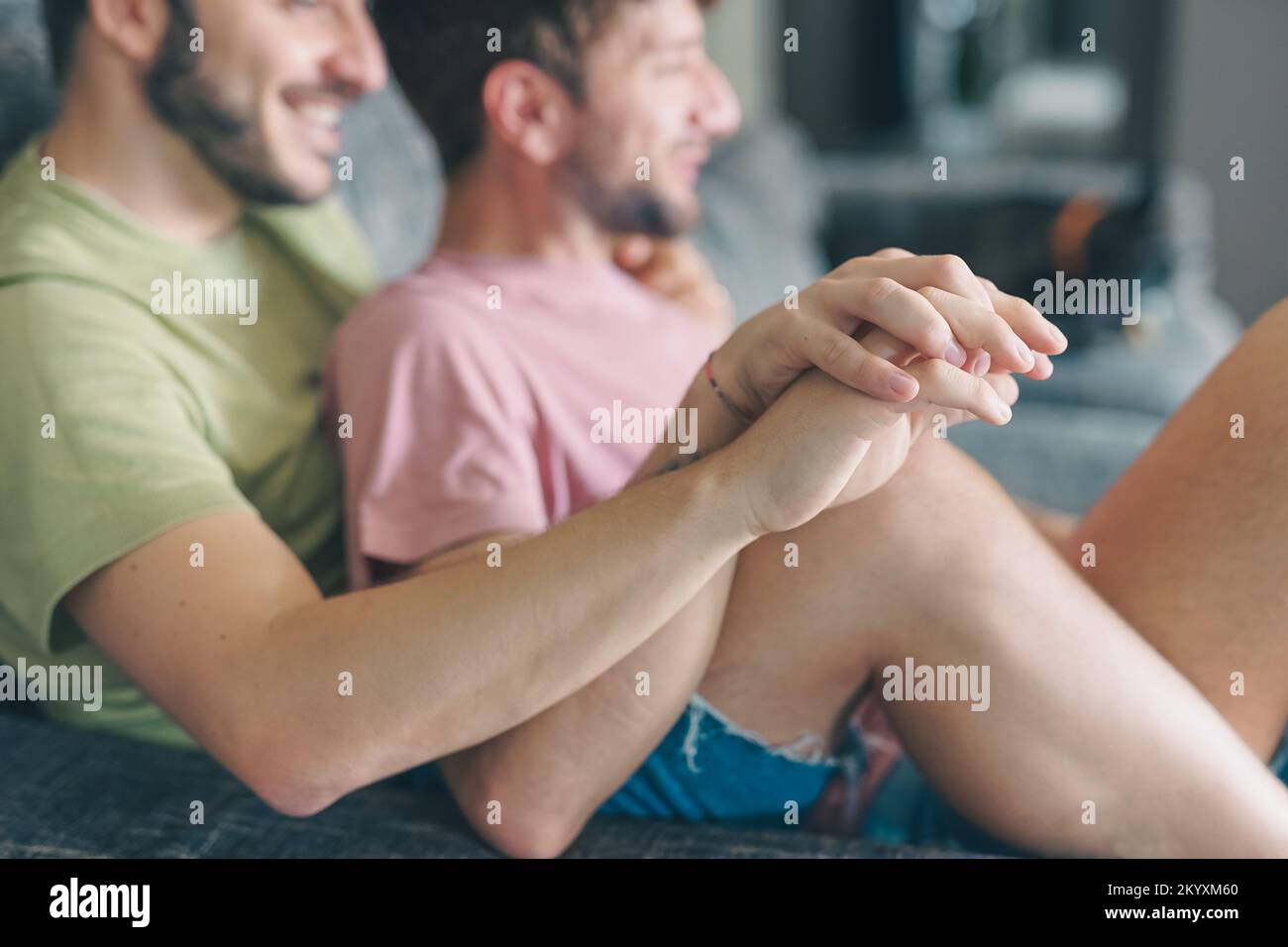 Giovane felice gay lgbtq mani coppia tenere a casa seduto sul divano - gay coppia guardando la tv seduta sul divano e divertirsi - Vintage filtro Foto Stock