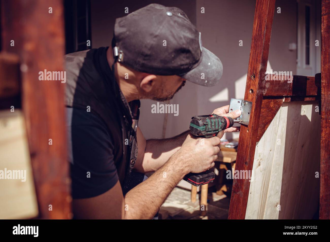 Manuale che avvita una cerniera della porta nel telaio della porta in legno. Ristrutturazione domestica Foto Stock
