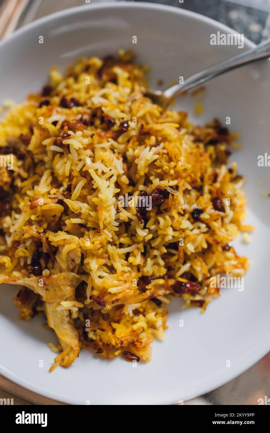 Primo piano con piatto di riso basmati persiano, Zereshk Polo ba Morgh, riso allo zafferano con barrioli e pollo Foto Stock