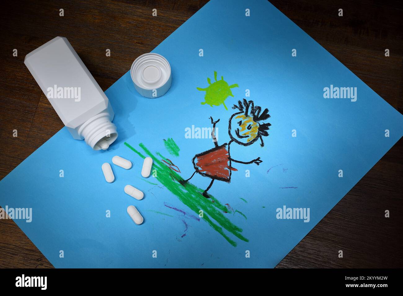 Scena di un contenitore aperto di farmaci su un’opera d’arte di un bambino che illustra i pericoli delle droghe non presidiate in presenza di bambini piccoli Foto Stock
