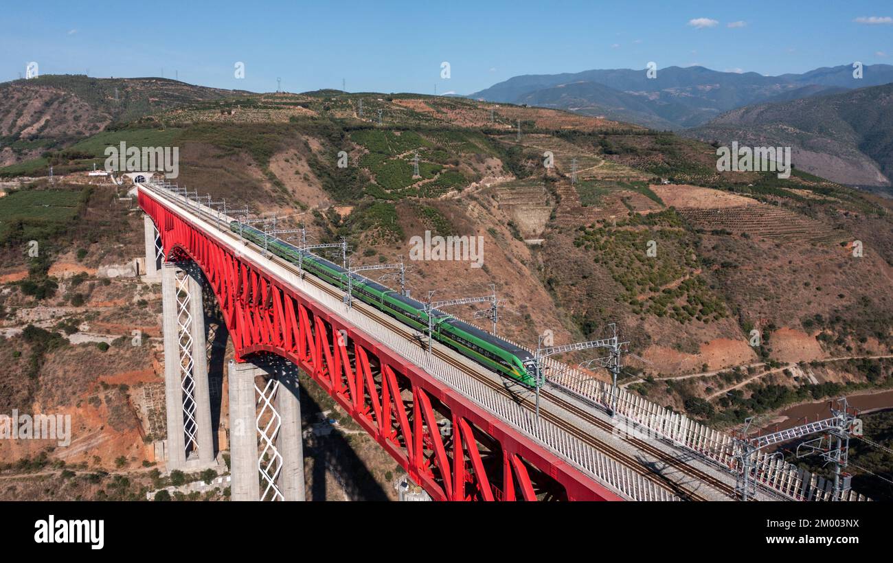 Kunming. 23rd Nov 2022. Questa foto aerea scattata il 23 novembre 2022 mostra un treno superveloce Fuxing che corre sul ponte YUANJIANG della ferrovia Cina-Laos nella provincia di Yunnan, nella parte sud-occidentale della Cina. A partire da venerdì, la China-Laos Railway ha gestito oltre 8,5 milioni di viaggi passeggeri e trasportato 11,2 milioni di tonnellate di merci dal suo lancio, un anno fa, ha detto l'operatore ferroviario cinese. Credit: HU Chao/Xinhua/Alamy Live News Foto Stock