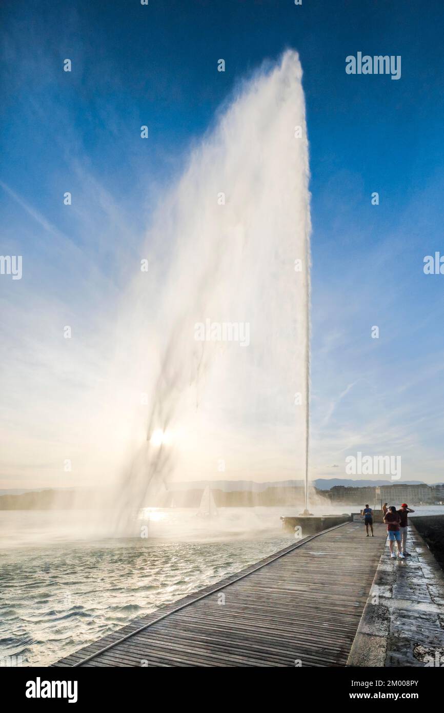I turisti che scattano foto si trovano direttamente sotto il Jet d'eau, il punto di riferimento nel bacino del Lago di Ginevra, Canton Ginevra, Svizzera, Europa Foto Stock