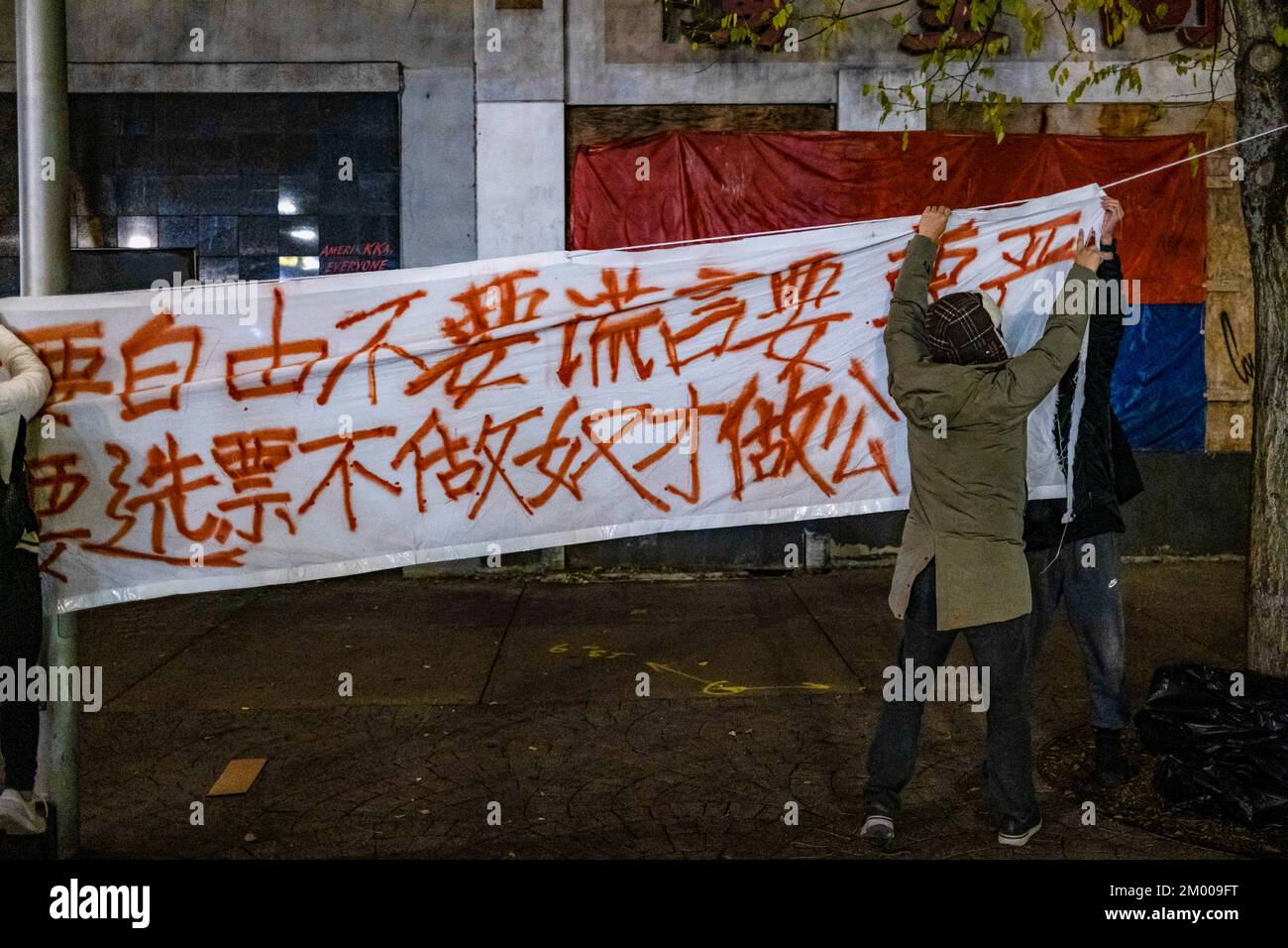 Boston, Stati Uniti. 02nd Dec, 2022. I dimostranti appendono una bandiera che recita: "Vogliamo cibo, non prove covide; vogliamo riforme, non rivoluzione culturale” davanti a una veglia a lume di candela al Memoriale di Tiananmen. Oltre 400 persone partecipano a una veglia a lume di candela al Tiananmen Memorial a Boston Chinatown per protestare contro la politica cinese di zero-covid e per commemorare le vittime del tragico incendio di Urumqi il 2 dicembre 2022. Credit: SOPA Images Limited/Alamy Live News Foto Stock