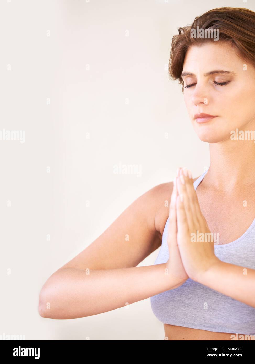 Tenere la mente e il corpo in grande forma. Primo piano di una bella donna che medita insieme con le sue palme. Foto Stock